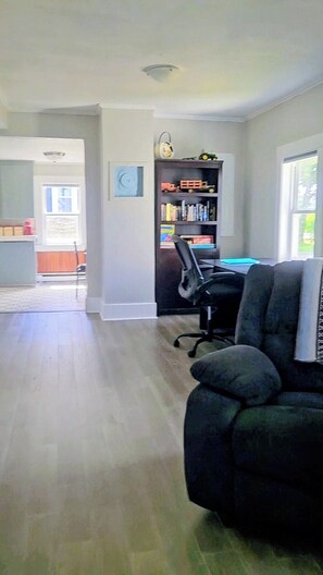 A room with a black office chair, a bookshelf with toys, and a window.