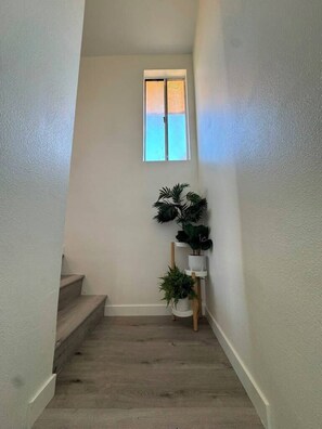 A narrow stairway with a small window at the top, wooden steps, and a white wall. - Stylish 2 bedroom + loft with rooftop patio and views near Beverly Hills (Beverly Hills)