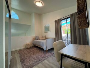 A bedroom with a bed, a small table, a chair, a window, and a view of the outside. - Stylish 2 bedroom + loft with rooftop patio and views near Beverly Hills (Beverly Hills)