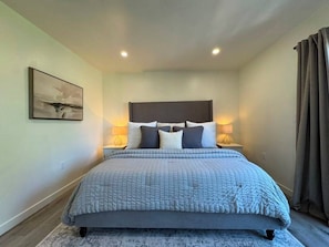 A bedroom with a bed, bedside lamps, a wall-mounted artwork, and a window with curtains. - Stylish 2 bedroom + loft with rooftop patio and views near Beverly Hills (Beverly Hills)