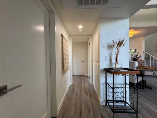 A hallway with a wooden floor, a white door, and a wall-mounted decorative item. - Stylish 2 bedroom + loft with rooftop patio and views near Beverly Hills (Beverly Hills)