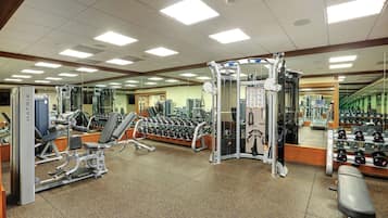 Une salle de sport équipée de divers appareils d’exercice, de miroirs et de supports pour les poids.