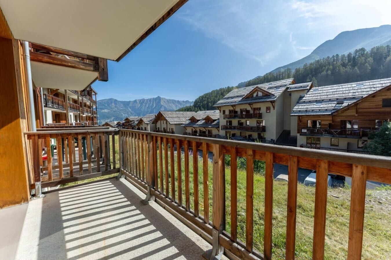 A balcony with a view of traditional chalet-style buildings and mountains in the background.