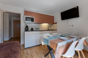Eine kompakte Küche mit Mikrowelle, Kaffeemaschine und einem Essbereich mit Tisch für zwei Personen.