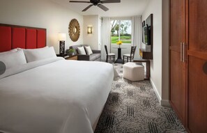 Ein Hotelzimmer mit einem großen Bett, einem Schreibtisch mit Stuhl, einem Fernseher und Blick auf einen Golfplatz.
