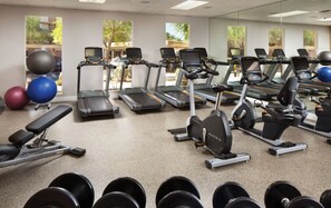 Ein Fitnessstudio mit Laufbändern, Crosstrainern und Kurzhanteln.