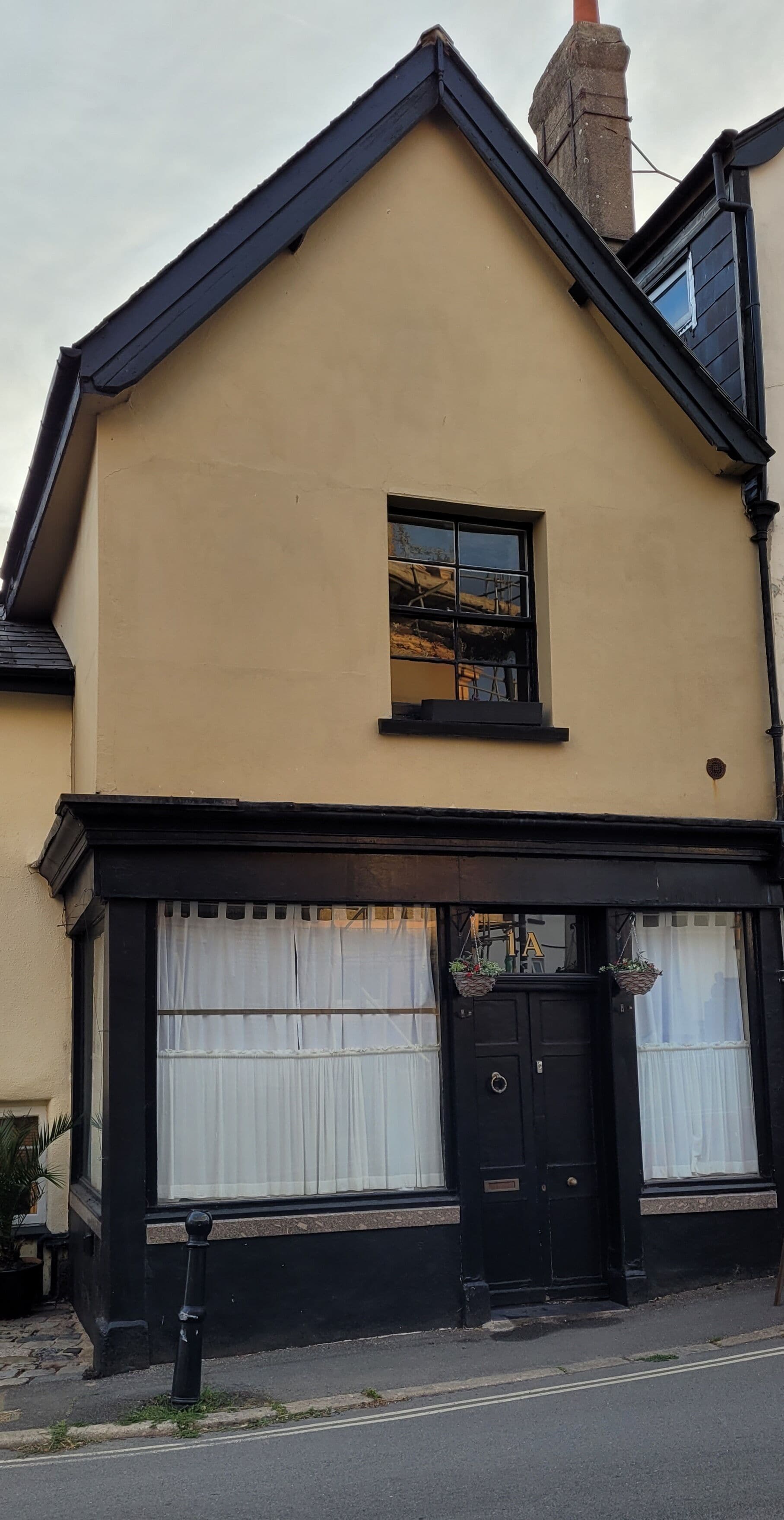 A two-story building with a black-framed window and a black door.