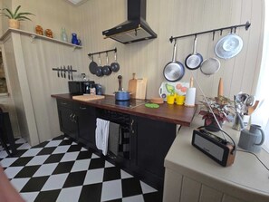 A kitchen with a checkered floor, a wooden countertop, and various kitchen utensils and appliances.