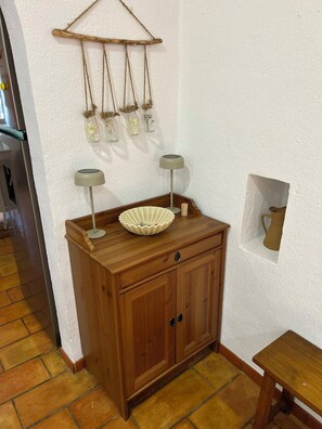 A wooden cabinet with a white bowl on top, two lamps, and a wall-mounted shelf with jars. - Belgerie in the Gard Department (Saint-André-de-Roquepertuis)