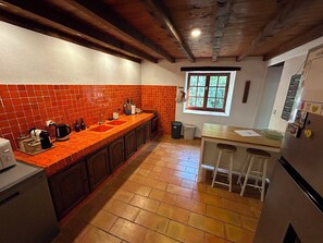 A kitchen with a red-tiled backsplash, wooden cabinets, a countertop with appliances, and a window with a view. - Belgerie in the Gard Department (Saint-André-de-Roquepertuis)