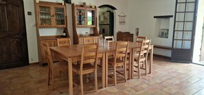 A dining area with a wooden table and chairs, a kitchen with cabinets, and a door labeled 'Bain'. - Belgerie in the Gard Department (Saint-André-de-Roquepertuis)