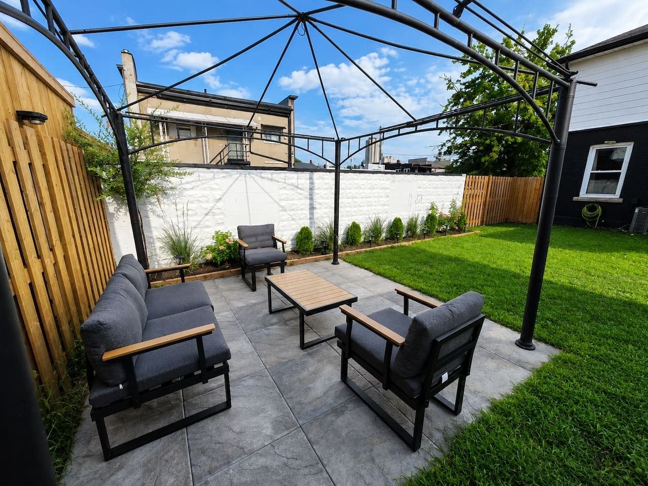 Une terrasse extérieure dotée d’une pergola, d’un espace salon et offrant une vue sur un immeuble d’habitation.