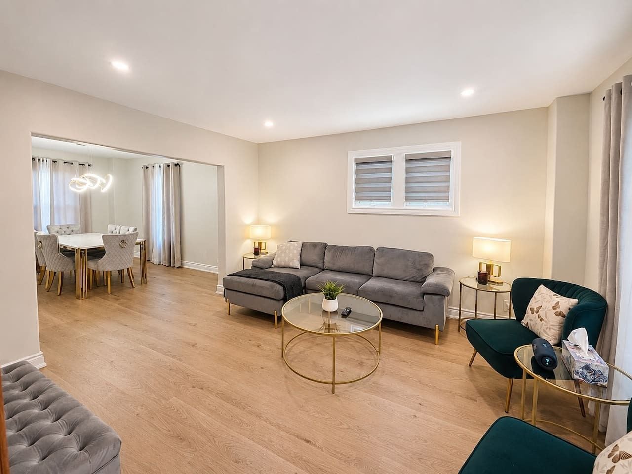 Un salon moderne avec un canapé gris, une table basse ronde et un coin repas comprenant une table et des chaises blanches.