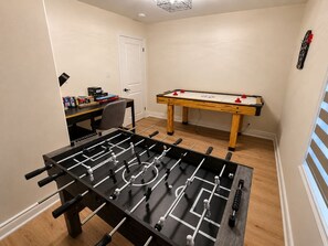 Une pièce équipée d’un baby-foot, d’une table de billard et d’un bureau avec divers objets.
