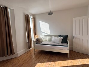 A room with a bed, a window, and a door. - Queens Coast Horizon – Stylish 4-Bedroom Townhouse by Queen's Park | Sleeps 10 (Brighton and Hove)
