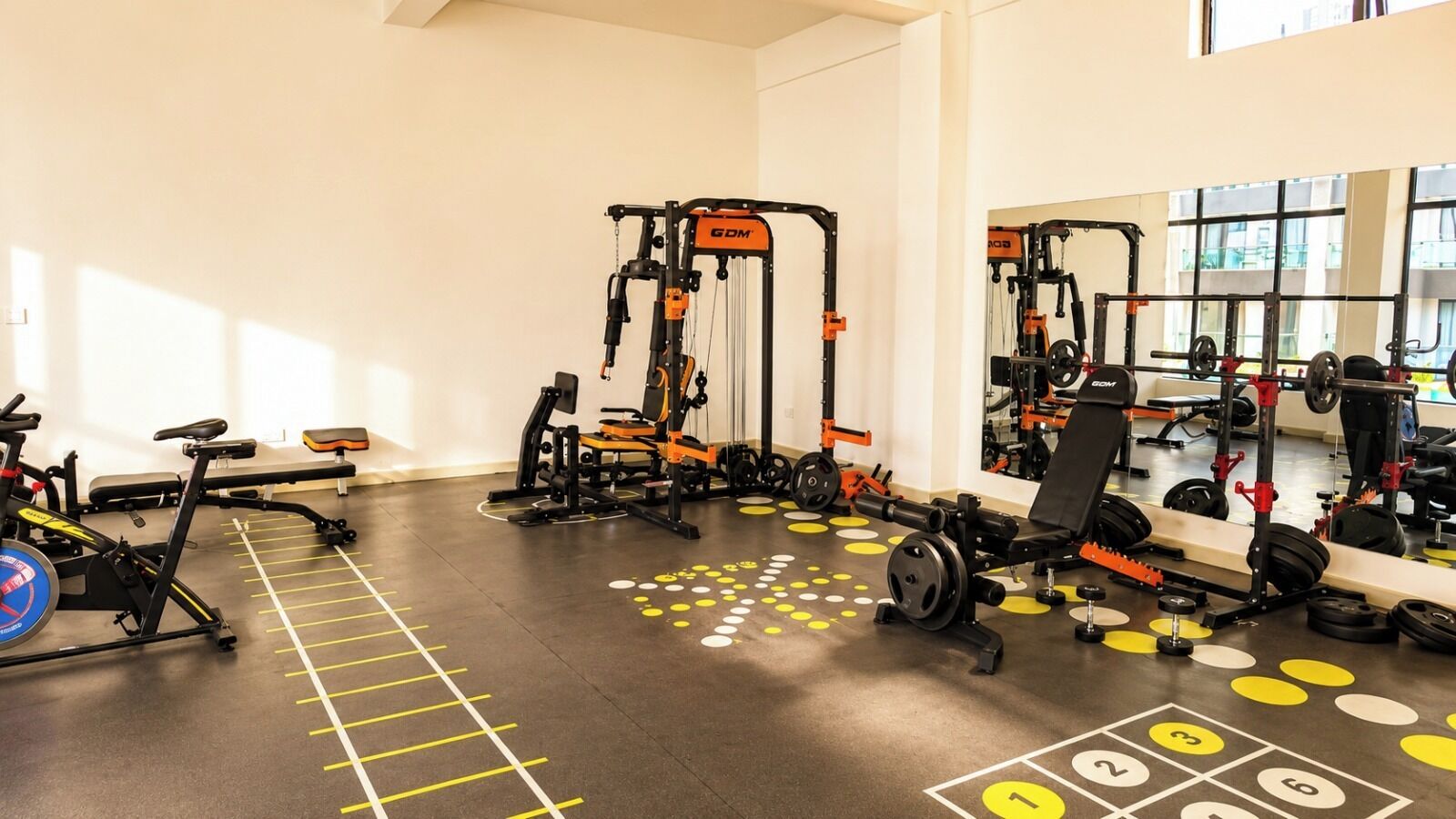 Ein Fitnessraum mit Trainingsgeräten, einem Rudergerät und einer Spiegelwand.