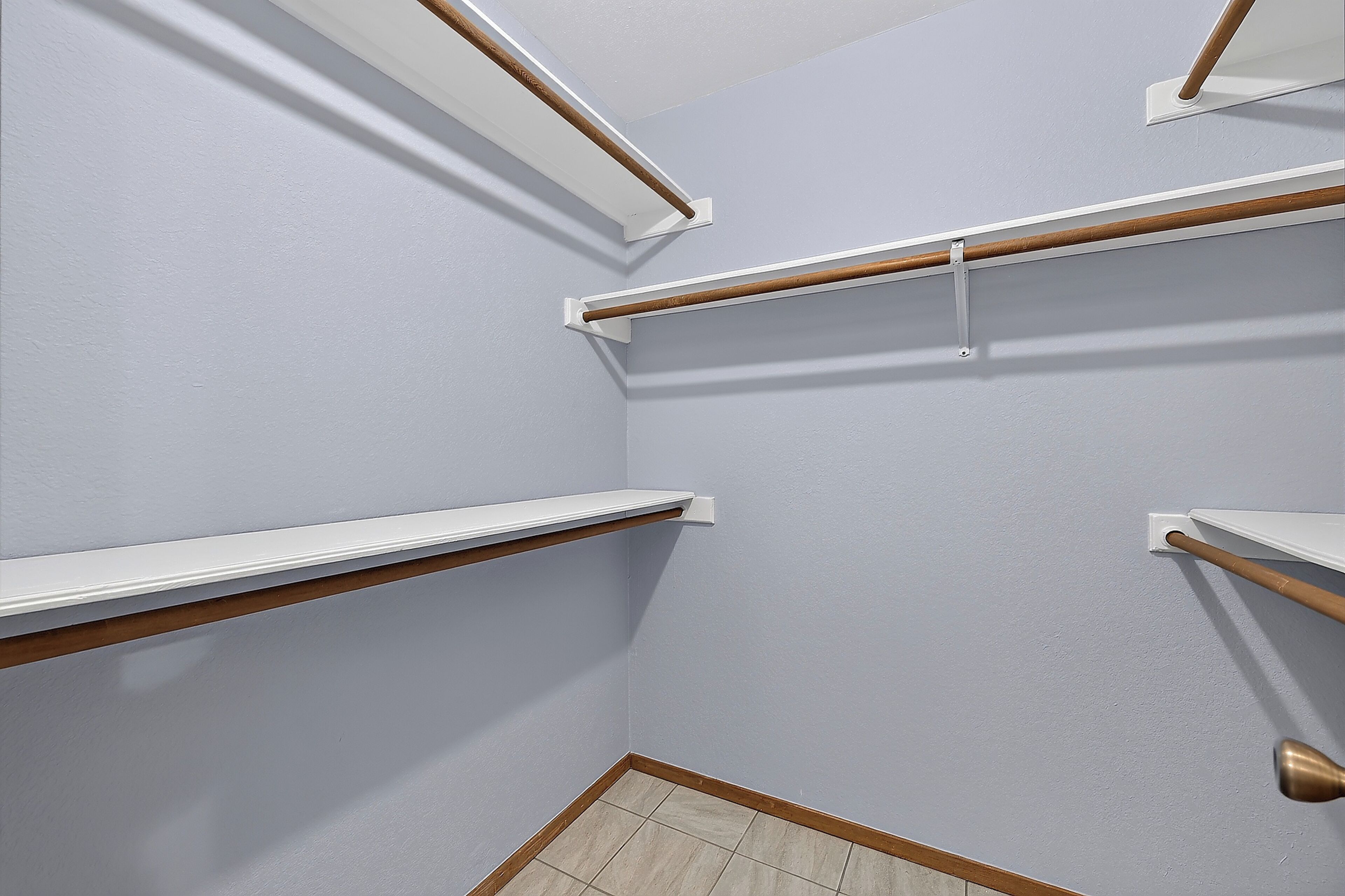 A corner of a room with white walls, wooden trim, and a tiled floor.