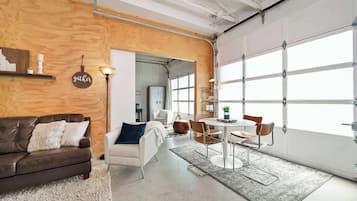 A modern interior with a wooden accent wall, a white sofa, a dining area with chairs, and a large garage door.