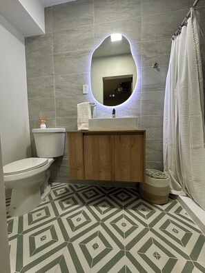 Ein Badezimmer mit Toilette, Waschbecken, Spiegel und Duschvorhang.