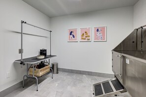 A kitchenette with a metal cart, a trash bin, and a stainless steel appliance.