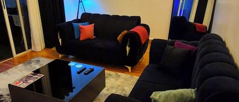 Moderni olohuone, jossa on musta sohvaryhmä, sohvapöytä ja suuri peili.