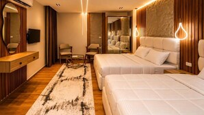 Quarto de hotel com duas camas, uma penteadeira de madeira, uma televisão e um espelho grande.