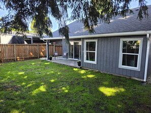 Une maison d’habitation dotée d’un patio couvert, d’une cour arrière clôturée et d’une pelouse.