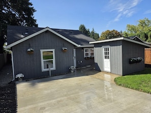 A two-story building with a grey exterior, a front door, and a small attached garage. - New & 9m to Portland (Vancouver)