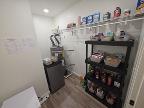 A compact kitchen with a refrigerator, a sink, and a pantry shelf stocked with food items. - New & 9m to Portland (Vancouver)