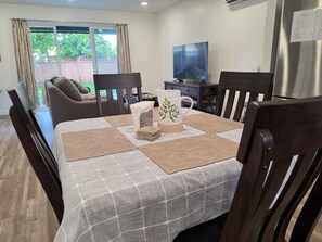 Un coin repas avec une table dressée pour quatre personnes, entourée de chaises en bois.