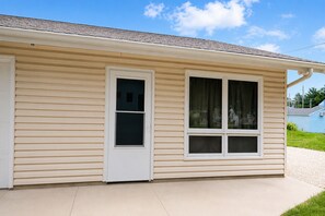 A single-story house with a beige siding exterior, a white front door, and two windows with curtains. - Canton River House, Steps from Culver-Stockton (Canton)