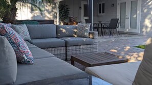A grey sofa with patterned cushions and a wooden table in an outdoor setting. - Old Town Family 4BR Hot Tub Swing Set Office A+Loc (Scottsdale)