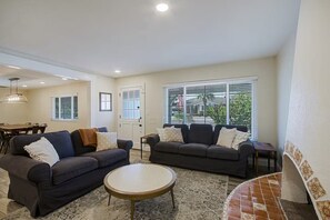 A living room with two sofas, a coffee table, and a dining area with a table and chairs. - Old Town Family 4BR Hot Tub Swing Set Office A+Loc (Scottsdale)