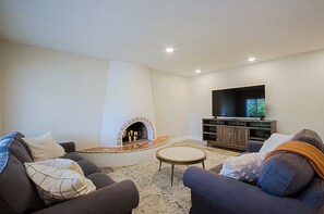 A living room with a fireplace, sofas, a coffee table, and a TV. - Old Town Family 4BR Hot Tub Swing Set Office A+Loc (Scottsdale)