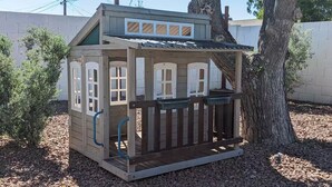 A wooden playhouse with a porch, windows, and a door. - Old Town Family 4BR Hot Tub Swing Set Office A+Loc (Scottsdale)