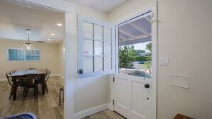 A room with a dining table and chairs, a white door with a window, and a ceiling light fixture. - Old Town Family 4BR Hot Tub Swing Set Office A+Loc (Scottsdale)