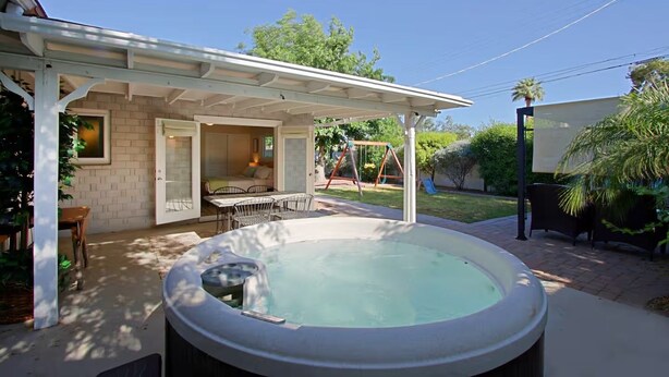 A backyard with a hot tub, a covered patio, a swing set, and a dining area. - Old Town Family 4BR Hot Tub Swing Set Office A+Loc (Scottsdale)