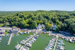 Vue aérienne d’une marina avec de nombreux quais et des bateaux, entourée d’une forêt dense.