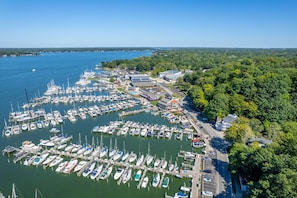 Eine Luftaufnahme einer Marina mit zahlreichen vertäuten Booten, umgeben von üppiger Vegetation und blauem Himmel.