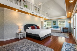 Une chambre spacieuse dotée d’un grand lit, d’un coin salon et offrant une vue sur l’extérieur.