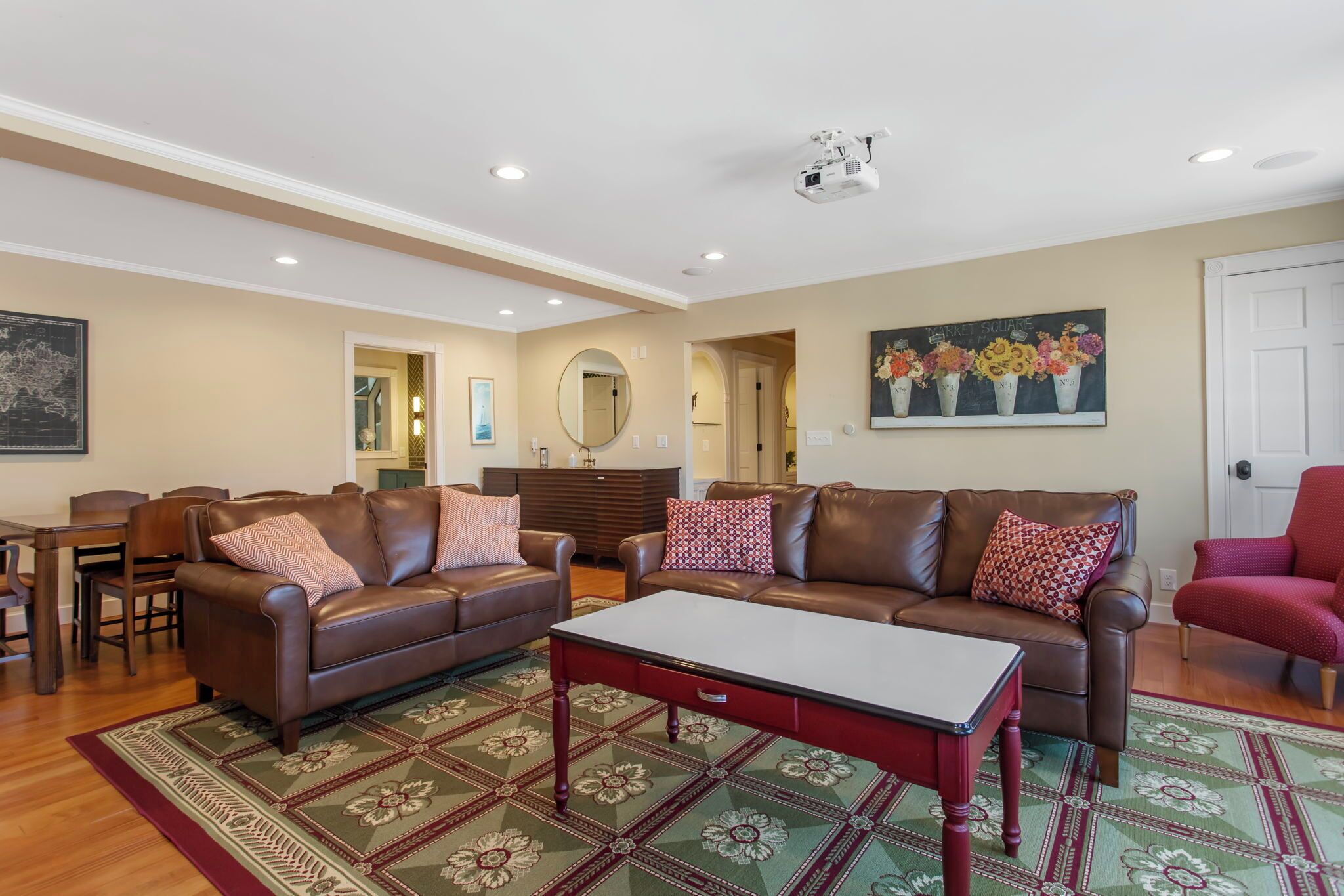 A spacious living room with leather sofas, a coffee table, and a patterned rug.