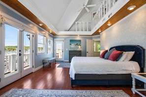 A bedroom with a large bed, a bench, and a view of the outdoors. - Wedding Cake House / Iconic Lake Macatawa Retreat (Holland)