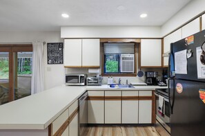 Eine moderne Küche mit weißen Schränken, einer eingebauten Mikrowelle, einem Toaster und einem Kühlschrank mit Magneten.