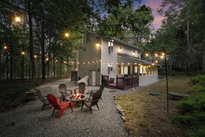 A house with a deck, outdoor seating, and string lights. - 3-bedroom chalet in superb Poconos with hot tube and close to lake (Poconos)