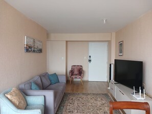 A living room with a sofa, a television, a patterned rug, and a door leading to another room. - Tranquil 3-bedroom apartment in charming Magdalena Del Mar close to everything. (Magdalena del Mar)