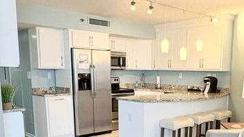 A modern kitchen with white cabinets, stainless steel appliances, and a central island with bar stools.