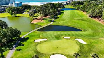 Un campo de golf con numerosos búnkeres, un estanque y vistas al océano.