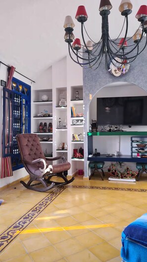 A living room with a chandelier, a television, and a blue-framed window.