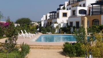 A pool area with lounge chairs and a clear sky.
