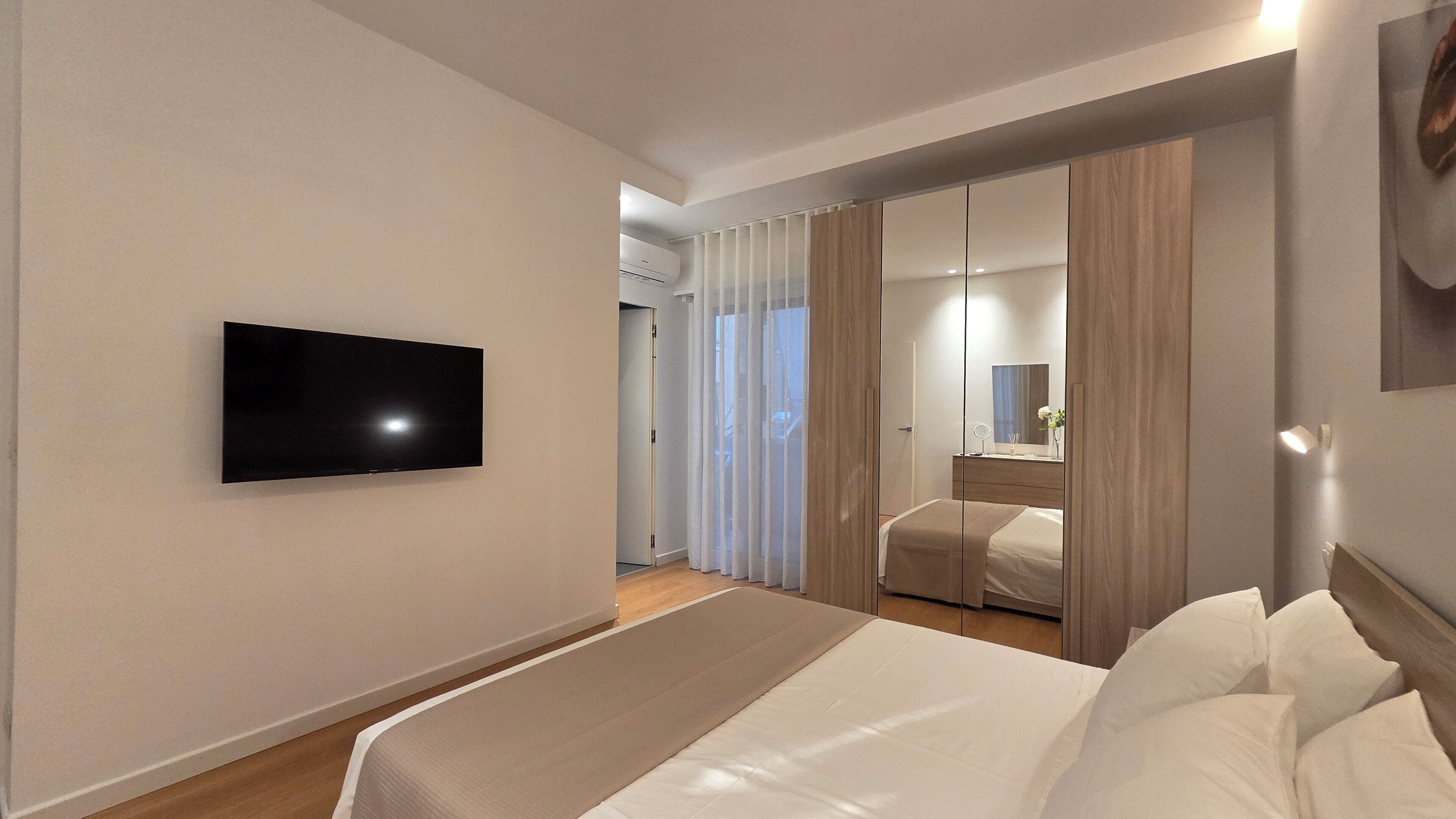 Une chambre d’hôtel équipée d’un lit, d’une télévision, d’un miroir et d’une armoire.